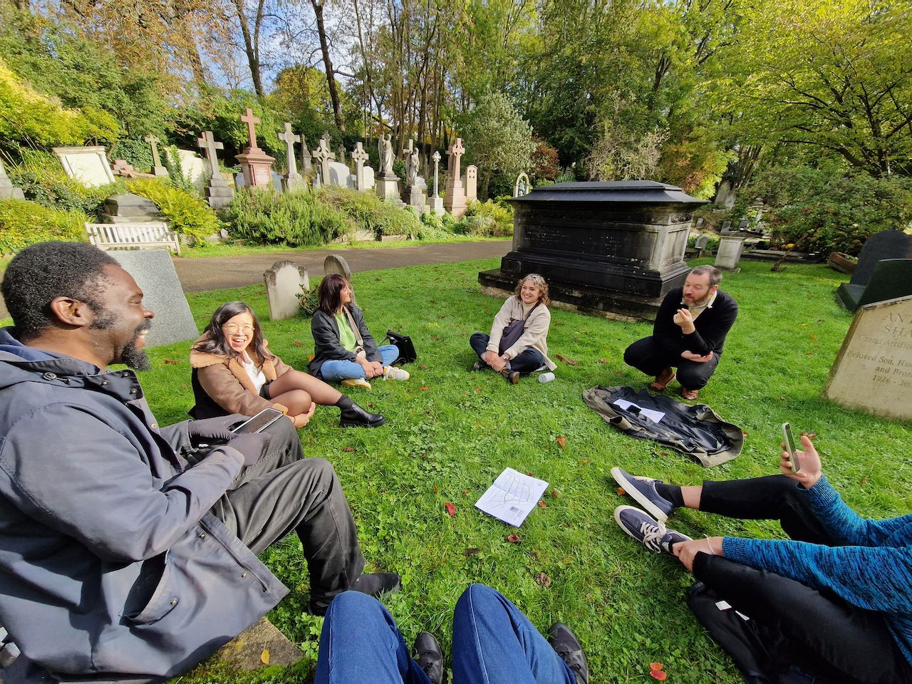 Group of people sitting in a cemetery.