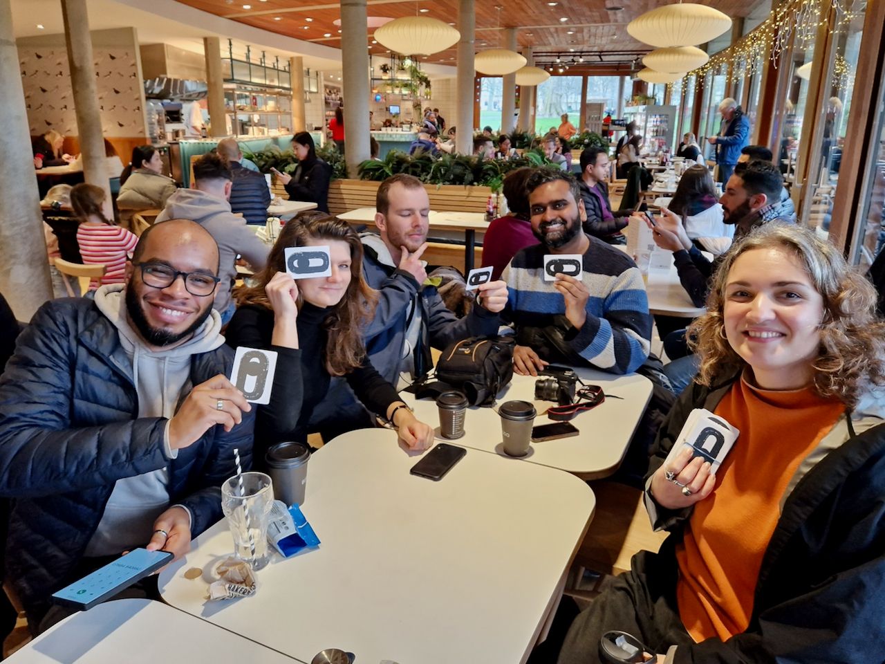 group of people holding Just Looking prompt cards in a cafe