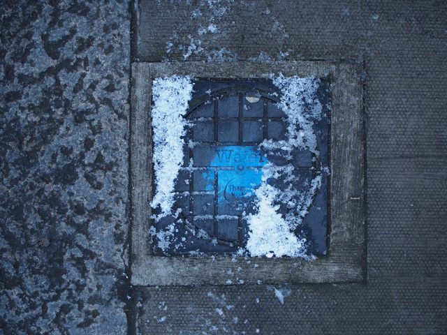 manhole cover with a blue spot of paint and ice