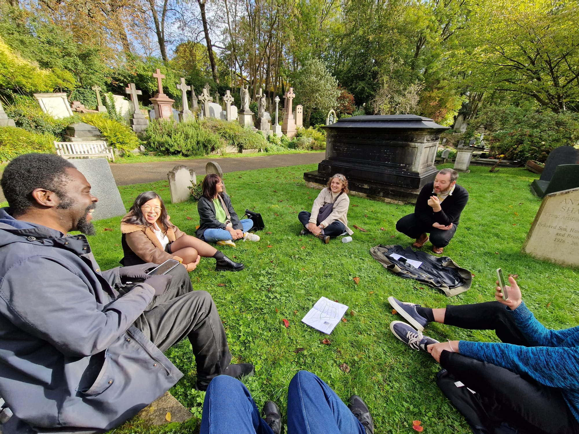 Group of friends sitting on the grass in a cemetery