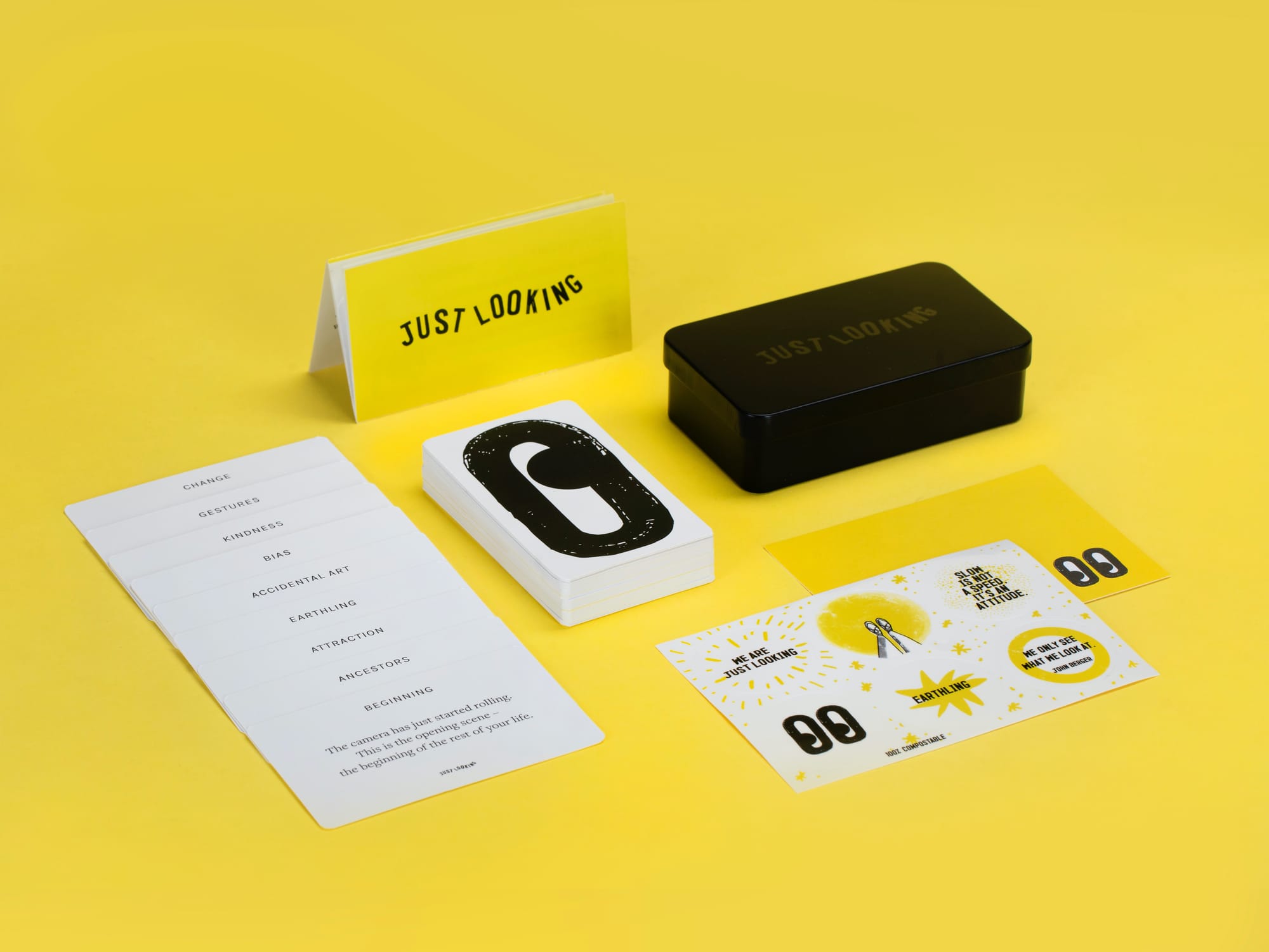 All the elements of the 60 Experiments in Looking (cards, tin, stickers) on a yellow background