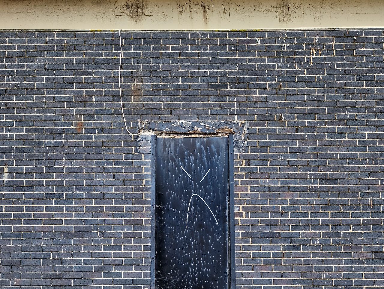 Black door with marks that look like a frown