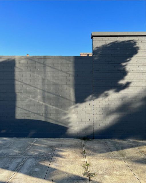 Blue sky, grey shadow on grey bricks.